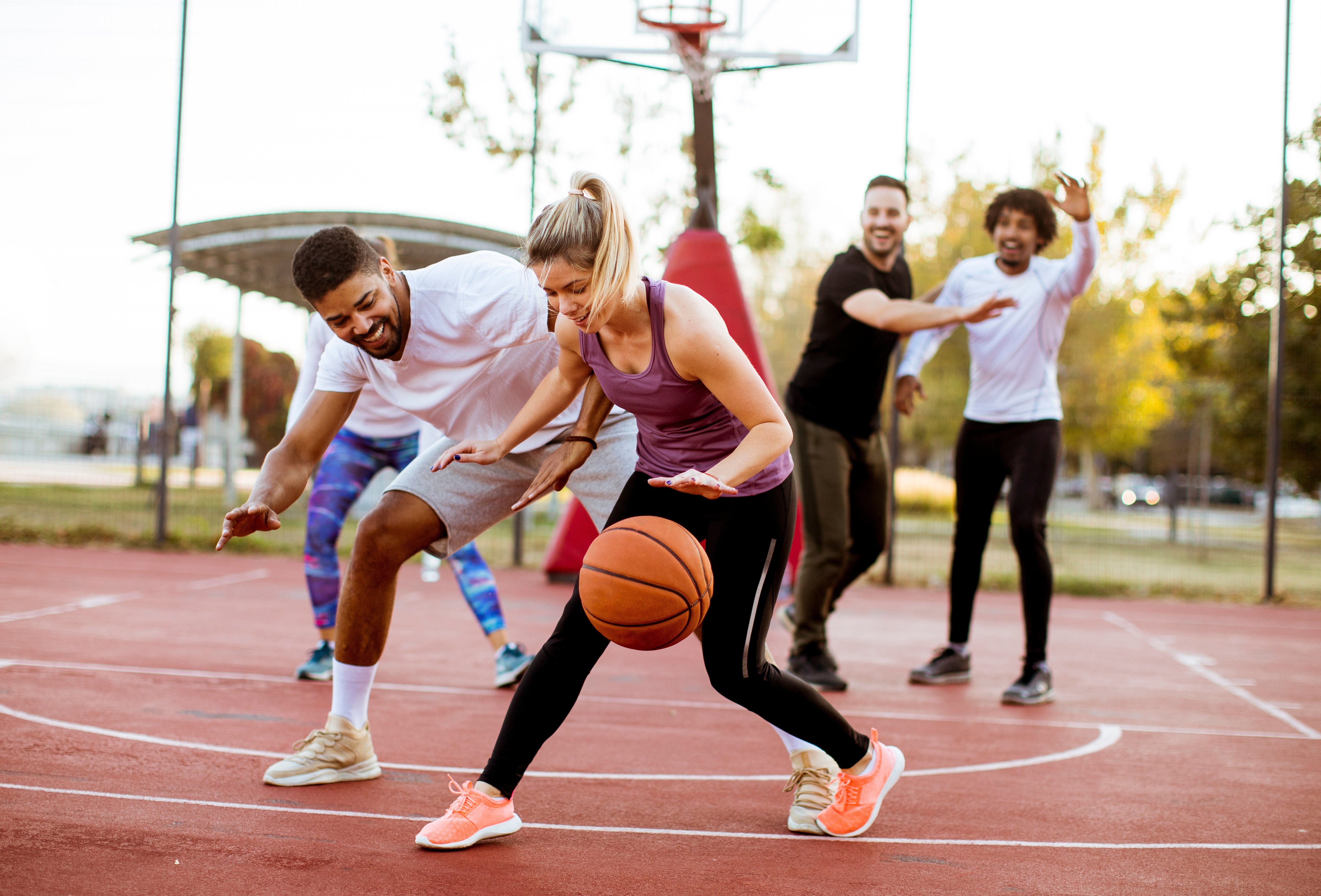 Community members playing basketball at an outdoor sports facility.