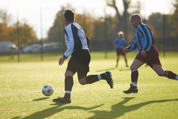 Football players using an outdoor sports facility, representing participation trends in sports facility management.